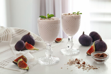 Delicious fig smoothies in glasses on white table