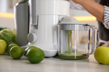 Young woman making tasty fresh juice at table in kitchen, closeup