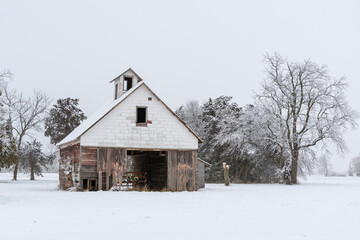 Old rustic wooden barn in the snow on a cold and foggy winter day.  LaSalle county, Illinois.