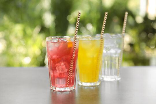 Delicious refreshing drinks in glasses on grey table outdoors