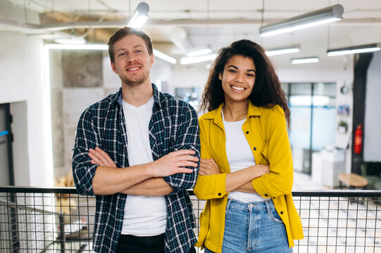 Portrait of business coworkers or student friends. Handsome caucasian man and beautiful african american woman work or study together. Young adult multiracial colleagues look at the camera, smiling