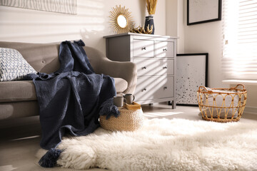 Comfortable sofa with soft plaid in stylish room interior