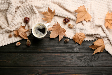 Flat lay composition with hot drink and warm plaid on black wooden table, space for text
