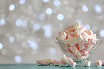 Delicious marshmallows in bowl on table against blurred background, closeup. Space for text