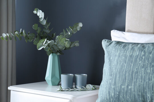 Beautiful eucalyptus branches and candles on nightstand in bedroom. Interior element