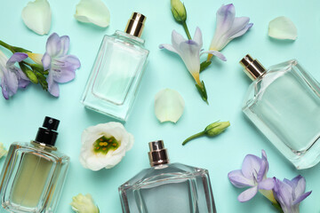 Flat lay composition of different perfume bottles and flowers on cyan background