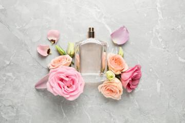 Flat lay composition with bottle of perfume and fresh flowers on light grey marble background
