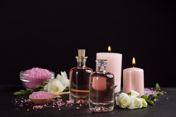 Beautiful spa composition with essential oil and candles on black table