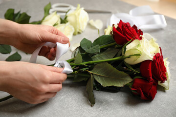 Fototapeta na wymiar Woman making luxury bouquet of fresh roses at grey table, closeup