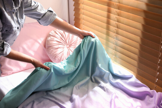 Woman Making Bed With New Colorful Linens In Children's Room, Closeup