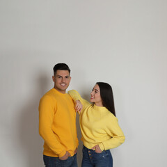 Happy couple wearing yellow warm sweaters on white background. Space for text