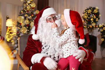 Fototapeta na wymiar Santa Claus and cute little girl in room decorated for Christmas