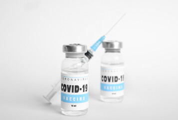 Vials with coronavirus vaccine and syringe on white background