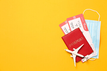 Flat lay composition with passport and protective mask on yellow background, space for text. Travel during quarantine