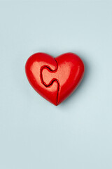 Red heart of two folded halves  on a blue background with copy space . Psychology and Valentine day  concept . Virtical.