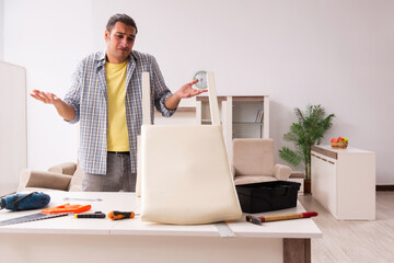 Young male carpenter repairing furniture at home