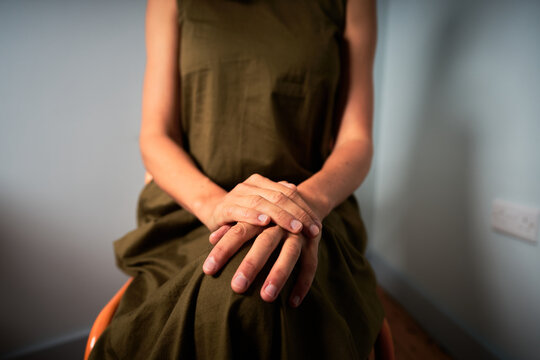 Young woman sitting in chair with hands resting on her knees