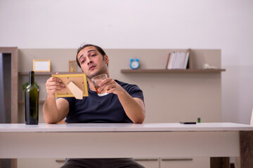 Young male alcoholic suffering from unhappy love at home