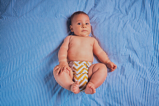 Little baby in reusable diaper on bed