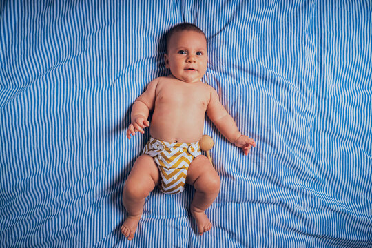 Little baby in reusable diaper on bed