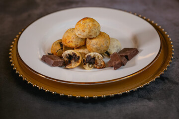 Cheese breads with chocolate filling, placed on a white plate on a concrete surface