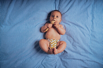 Baby on bed with wooden rattle
