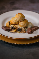 Cheese breads with chocolate filling, placed on a white plate on a concrete surface