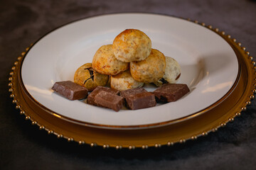 Cheese breads with chocolate filling, placed on a white plate on a concrete surface