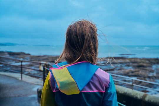 Young woman in raincoat standing by the seaside