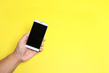 Fototapeta na wymiar View of a hand holding a smartphone isolated on yellow background 