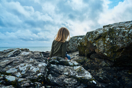 Preschooler sitting on rock by the sea