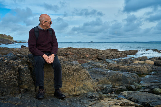 Senior man sitting on a rock by the sea