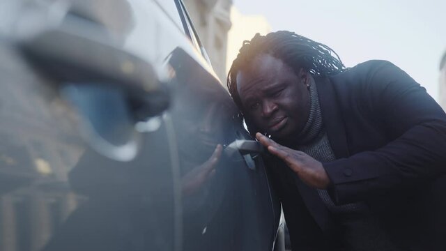 Sad african american black businessman looking at the scratches on his new car. High quality 4k footage