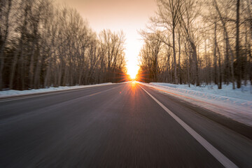Obraz premium Driving toward a winter sunset on a rural highway
