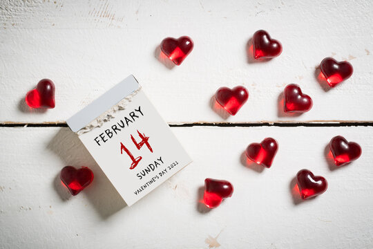 tear-off calendar with Valentine's Day 2021 and heart decoration on top on wooden background