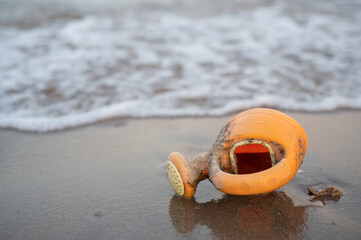Obraz premium an orange plastic watering can found along the empty beach