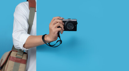 Male hand holding digital camera on blue background,copy space for text