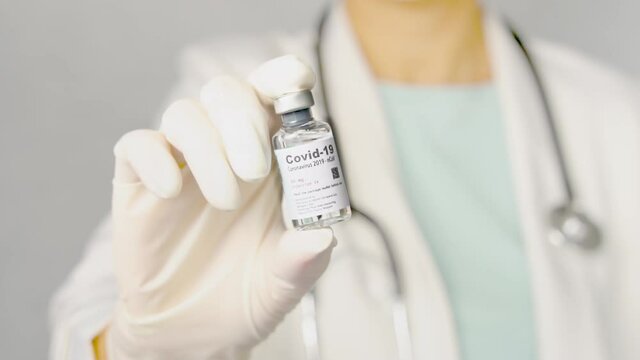 Slow motion of female doctor in white gown showing updates safe and effective mRNA Covid-19 Vaccine vial - The successful vaccination from COVAX collaborating. Hope, Partners, Pandemic, Action plan.