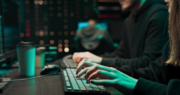 Team of Boy and Girl Hackers Organize Advanced Virus Attack on Corporate Servers. They Work Together. Place is Dark and Has Multiple displays.