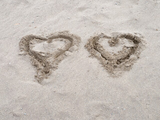 two Valentines Day hearts of love drawn 1n the sand on a beach