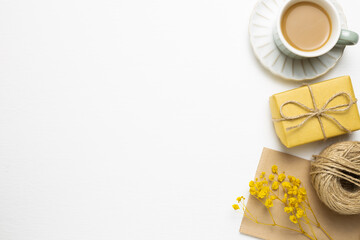 Anniversary concept. Yellow gift box, cup of coffee, card with dry flowers on white background. flat lay, top view, copy space