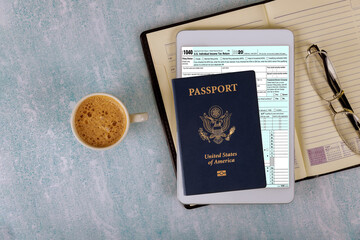 Preparation application 1040 U.S. Individual Income Tax on American passport with eyeglasses in the E-form digital tablet
