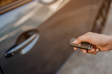 Close up hands woman pressing remote systems key near car for lock of blue  car near street road driving..Holiday,travel and vacation concept.