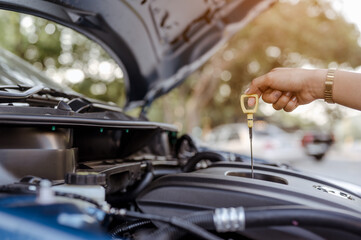 A woman self service use dipstick checking engine oil level car vehicle,professional maintenance and repair before travel transportation for safety driving on street road.Holiday,travel and vacation