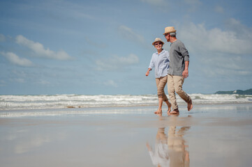 Senior couple running on the beach at sunny day. Plan life insurance with the concept of happy...