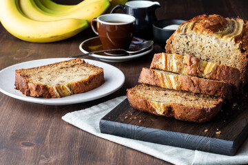 Close up of a sliced banana loaf with one slice on a small plate ready for eating.