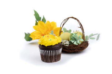 a chocolate cupcake with yellow frosting in an easter setting isolated on white