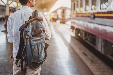 Naklejka premium Asian man traveler with backpack in the railway, Backpack at the train station with a traveler. Travel concept. Man traveler tourist walking at train station.