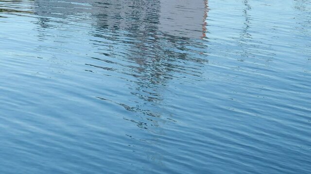 Reflections of a fishing boat in the moving ocean.