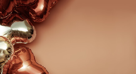 Brown and silver foil balloons in the shape of a heart on the left side with space for text. Heart-shaped balloon as a symbol of Valentine's Day